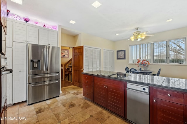 kitchen featuring black electric stovetop, ceiling fan, stainless steel fridge, and dark stone countertops