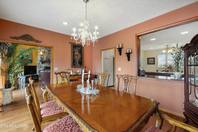 dining room with ceiling fan with notable chandelier and light wood-type flooring