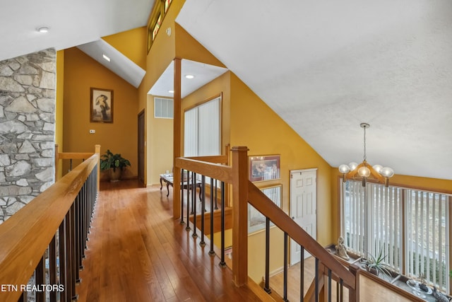 hall featuring a chandelier, wood-type flooring, and vaulted ceiling