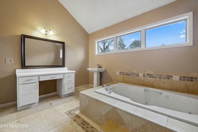 bathroom with a relaxing tiled tub, sink, and vaulted ceiling