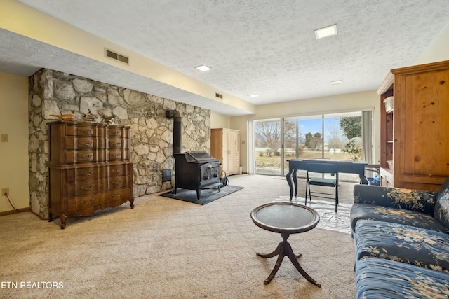 living room featuring a wood stove, light carpet, and a textured ceiling