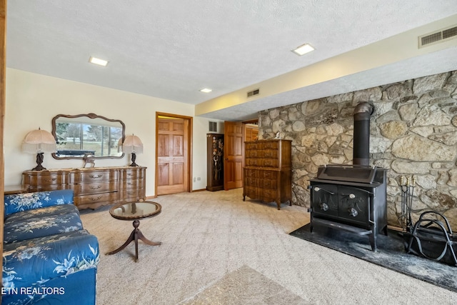 living room with carpet flooring, a wood stove, and a textured ceiling