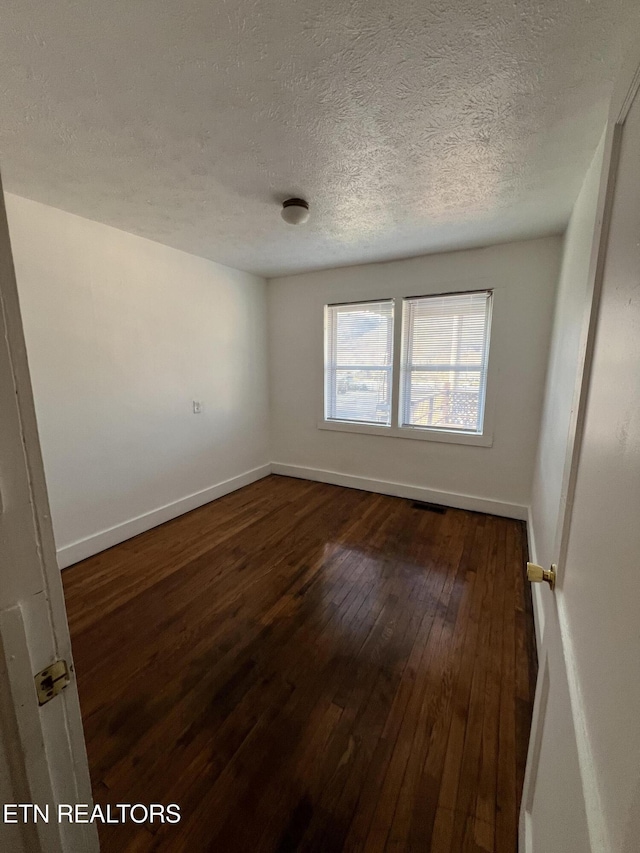 spare room with dark wood-type flooring and a textured ceiling