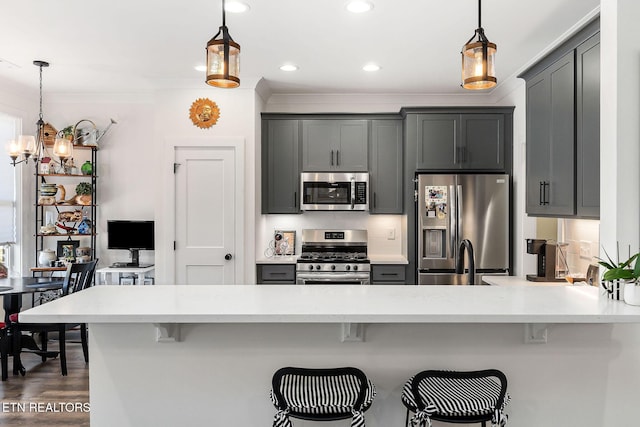 kitchen with a kitchen bar, backsplash, stainless steel appliances, and hanging light fixtures