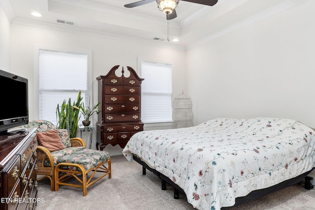 carpeted bedroom with a raised ceiling, ceiling fan, and ornamental molding