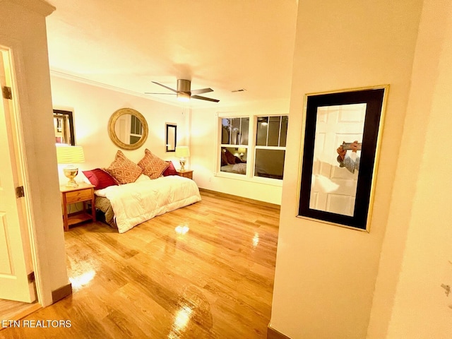 bedroom featuring hardwood / wood-style flooring, ceiling fan, and ornamental molding