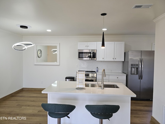 kitchen with pendant lighting, white cabinets, sink, tasteful backsplash, and stainless steel appliances