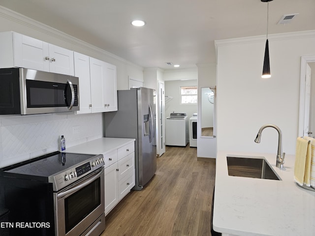 kitchen with white cabinets, decorative light fixtures, sink, and appliances with stainless steel finishes