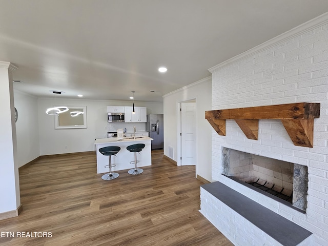 kitchen with a breakfast bar, dark hardwood / wood-style floors, a fireplace, white cabinetry, and stainless steel appliances