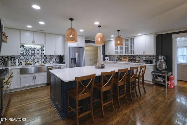 kitchen with white cabinets, sink, dark hardwood / wood-style floors, a kitchen island, and stainless steel appliances