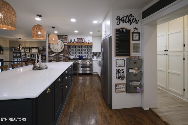 kitchen featuring pendant lighting, white cabinets, dark hardwood / wood-style floors, a kitchen island, and stainless steel appliances