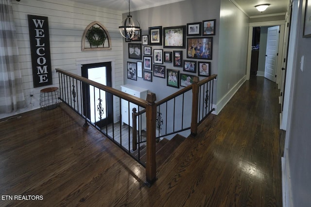 corridor featuring a notable chandelier, crown molding, and dark wood-type flooring