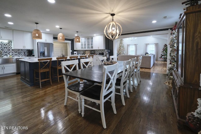 dining space featuring sink, dark hardwood / wood-style flooring, and an inviting chandelier