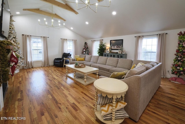 living room featuring hardwood / wood-style floors, an inviting chandelier, a healthy amount of sunlight, and beam ceiling