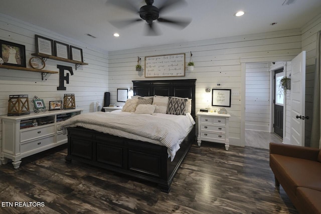 bedroom with dark hardwood / wood-style floors, ceiling fan, and wooden walls