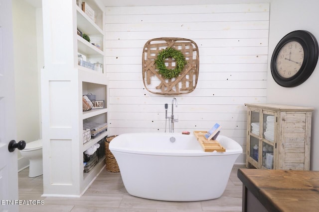 bathroom featuring wooden walls, a bathtub, hardwood / wood-style floors, and toilet