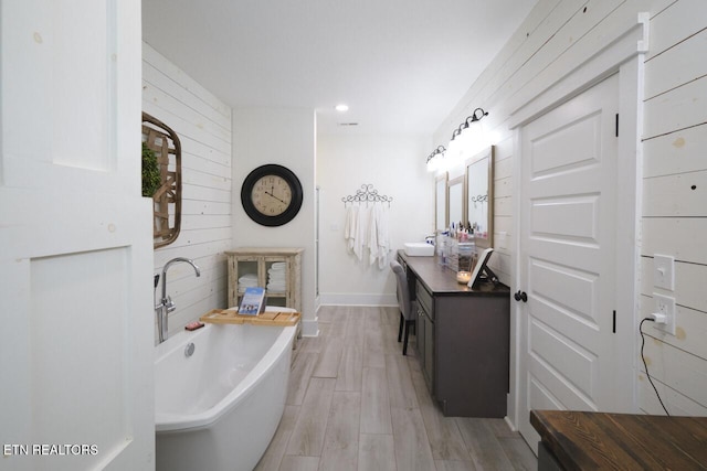 bathroom with a bathing tub, vanity, and wood-type flooring