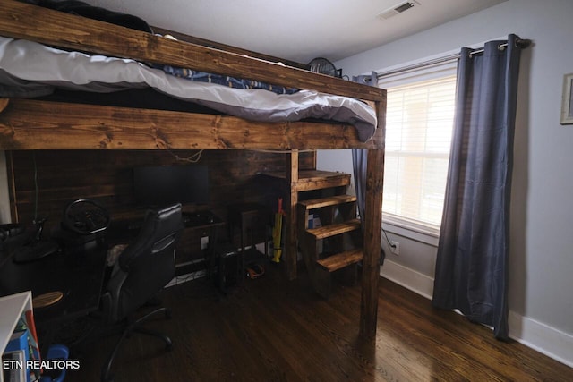 bedroom with multiple windows and dark hardwood / wood-style floors