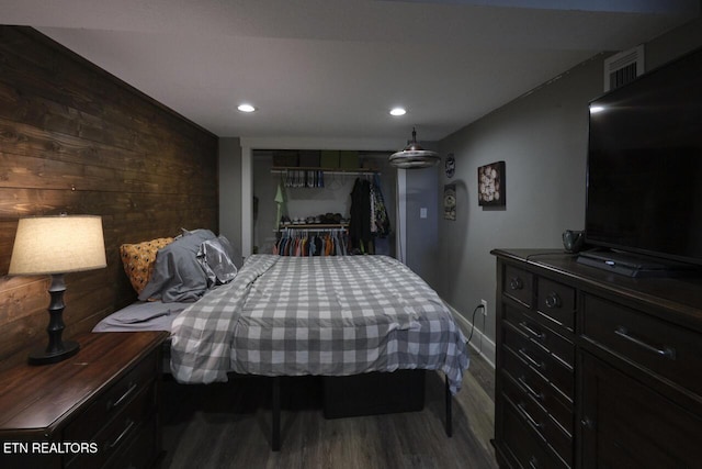 bedroom featuring a closet, dark wood-type flooring, and wood walls