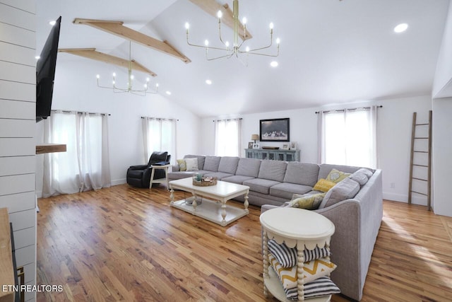 living room with an inviting chandelier, hardwood / wood-style floors, high vaulted ceiling, and a healthy amount of sunlight