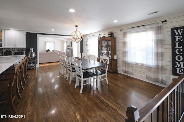 dining space featuring dark wood-type flooring and an inviting chandelier