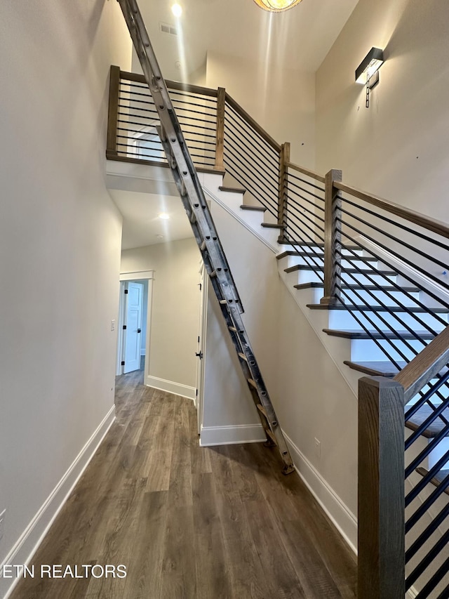 stairway featuring a high ceiling and wood-type flooring