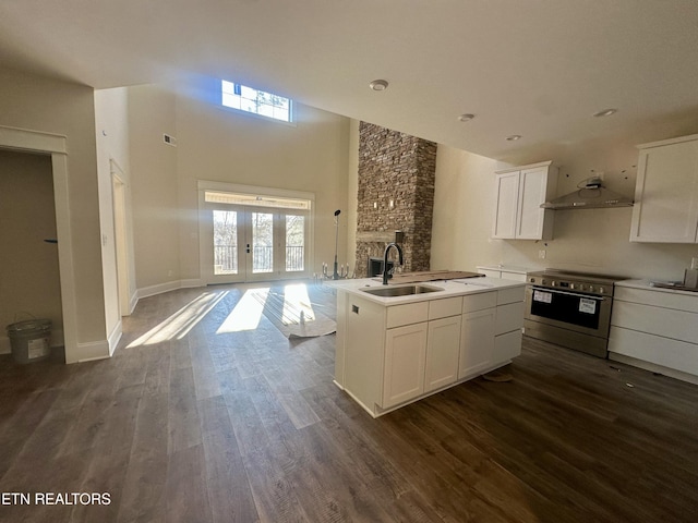 kitchen featuring white cabinetry, stainless steel range with electric stovetop, sink, dark wood-type flooring, and an island with sink