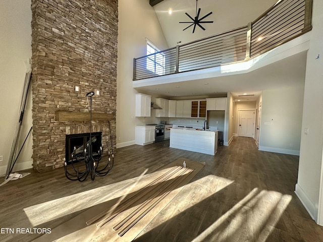 unfurnished living room with sink, dark hardwood / wood-style floors, a high ceiling, and ceiling fan