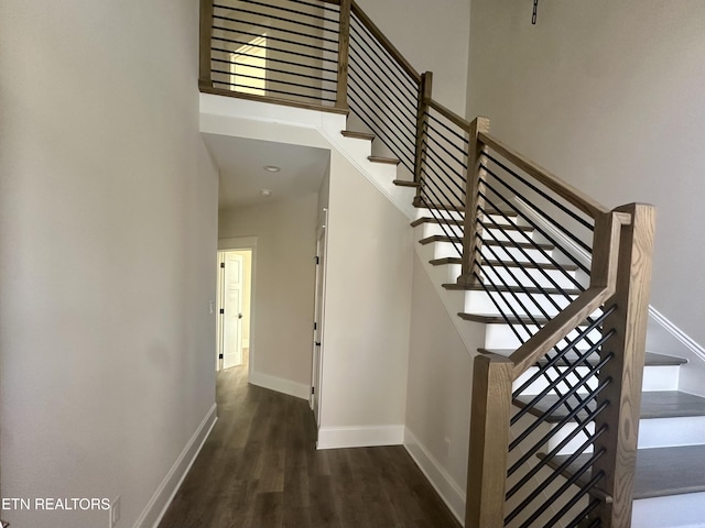 stairs with baseboards, a high ceiling, and wood finished floors