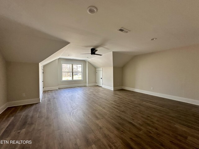additional living space featuring vaulted ceiling, baseboards, visible vents, and dark wood-style flooring
