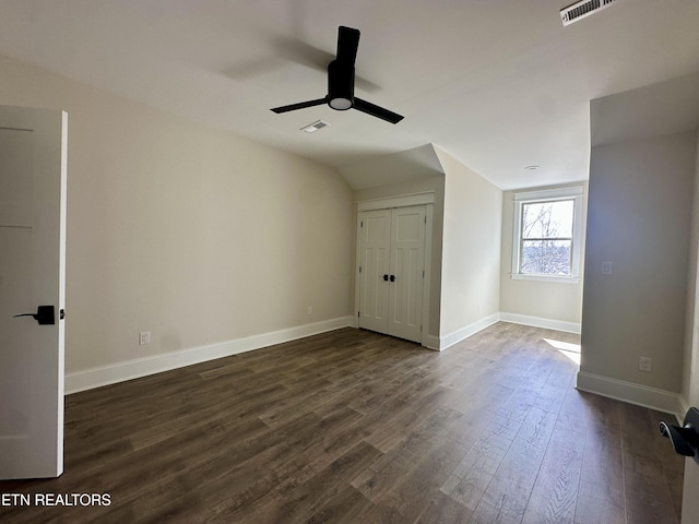 interior space with dark wood-style floors, visible vents, baseboards, and vaulted ceiling