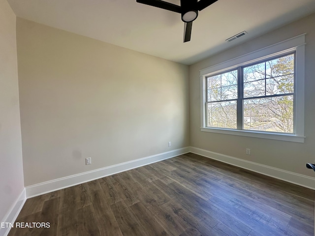 empty room featuring visible vents, a ceiling fan, baseboards, and dark wood-style flooring