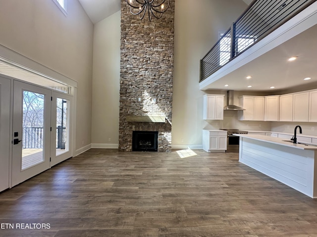 kitchen with dark wood-type flooring, wall chimney exhaust hood, stainless steel electric range, and a sink