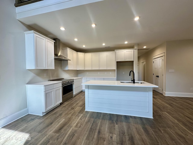 kitchen with dark wood finished floors, an island with sink, stainless steel electric range, a sink, and wall chimney range hood