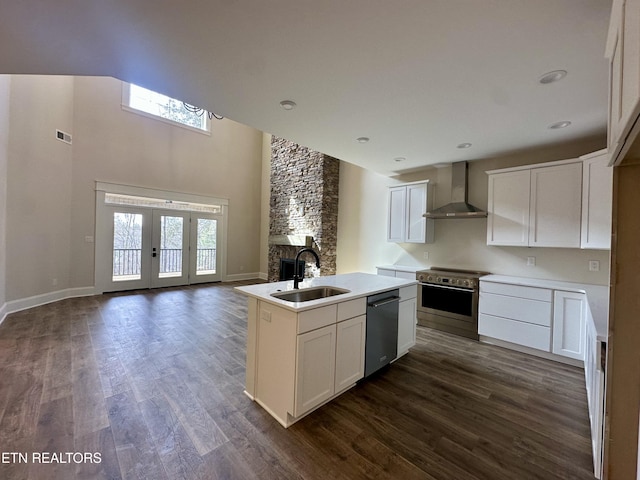 kitchen featuring dark wood-style floors, a sink, appliances with stainless steel finishes, wall chimney exhaust hood, and open floor plan