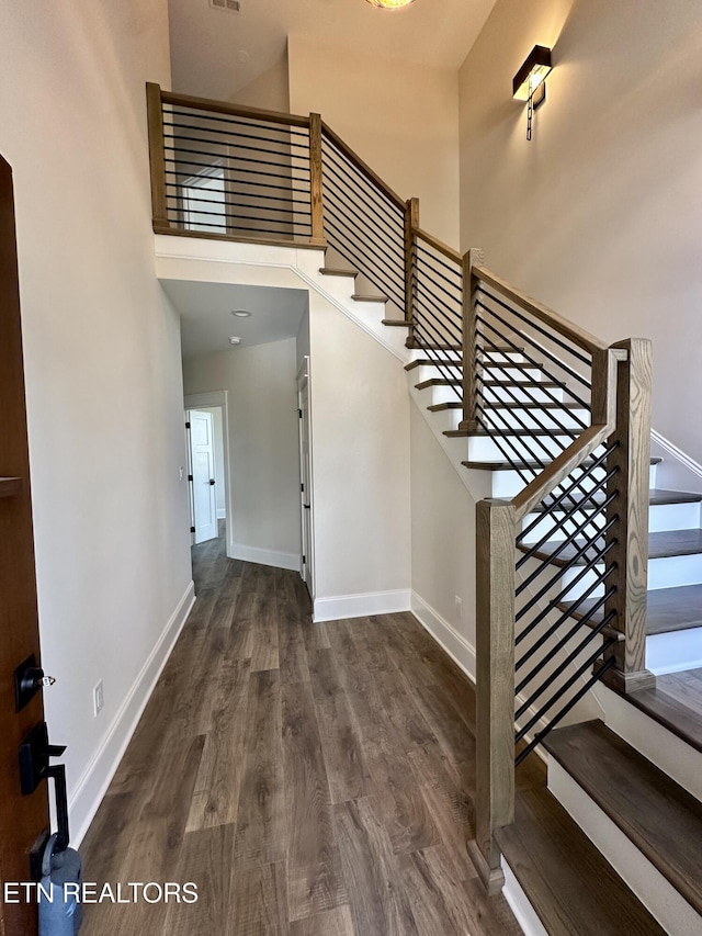 foyer entrance with stairway, baseboards, a high ceiling, and wood finished floors