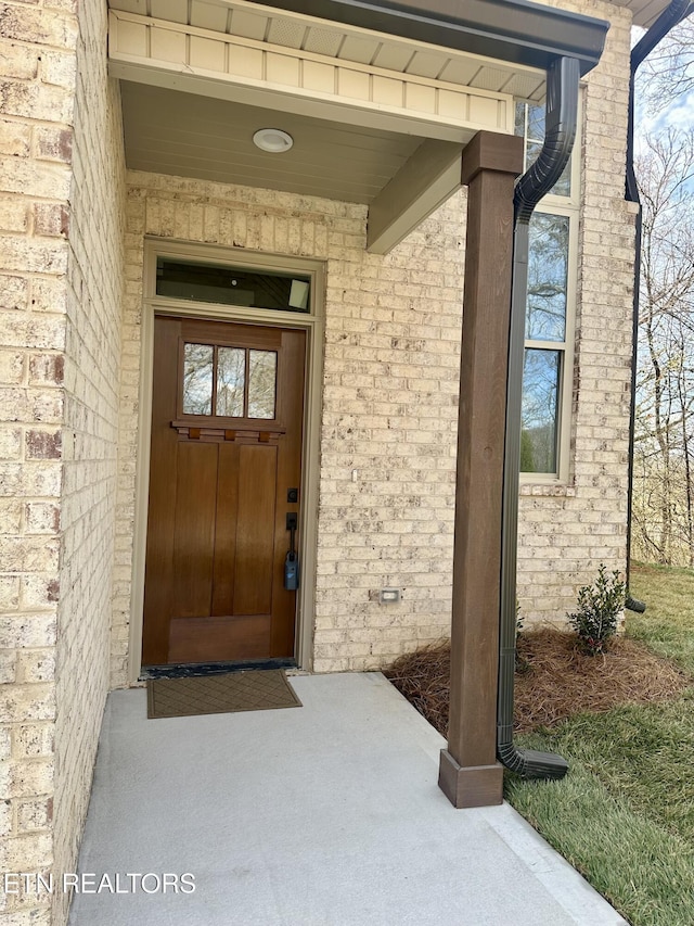 view of exterior entry featuring brick siding