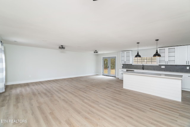 unfurnished living room with french doors, light hardwood / wood-style floors, and sink