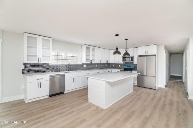 kitchen with white cabinets, decorative light fixtures, a kitchen island, and stainless steel appliances