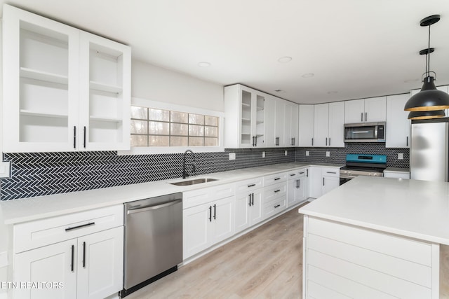 kitchen featuring white cabinetry, sink, decorative light fixtures, decorative backsplash, and appliances with stainless steel finishes