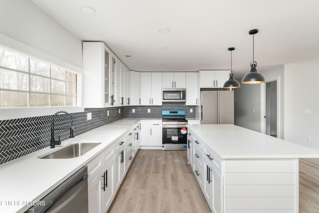 kitchen with sink, white cabinets, stainless steel appliances, and a kitchen island