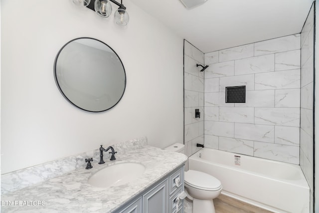 full bathroom with hardwood / wood-style floors, vanity, toilet, and tiled shower / bath