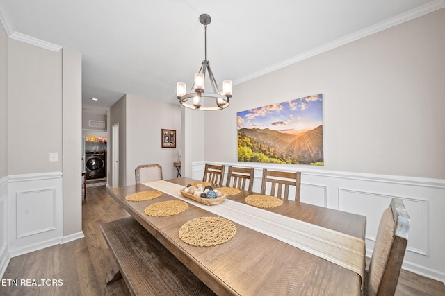 dining space featuring dark hardwood / wood-style flooring, washer / clothes dryer, an inviting chandelier, and crown molding