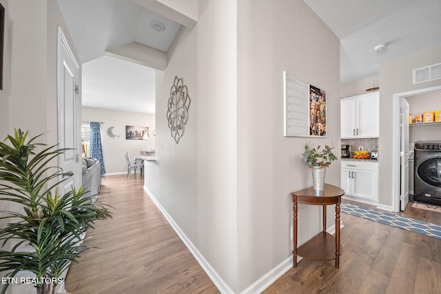 corridor with washer / dryer and hardwood / wood-style flooring