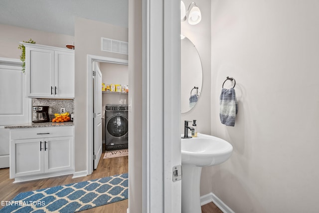 bathroom with tasteful backsplash, hardwood / wood-style flooring, a textured ceiling, and washer / dryer