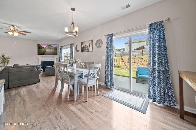 dining area with light hardwood / wood-style floors and ceiling fan with notable chandelier