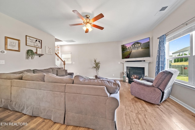 living room with light hardwood / wood-style flooring, plenty of natural light, and ceiling fan