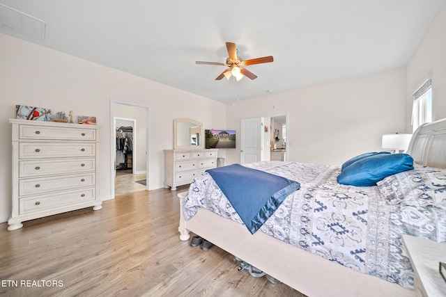 bedroom featuring connected bathroom, ceiling fan, light hardwood / wood-style floors, a walk in closet, and a closet