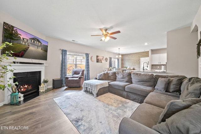 living room with ceiling fan, light wood-type flooring, and sink