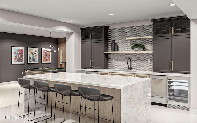 kitchen featuring tasteful backsplash, stainless steel dishwasher, sink, a kitchen island, and pool table